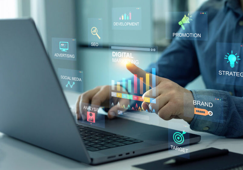 Person using laptop with digital marketing icons.